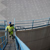 Man in yellow clothing and construction helmet walking up an oil terminal